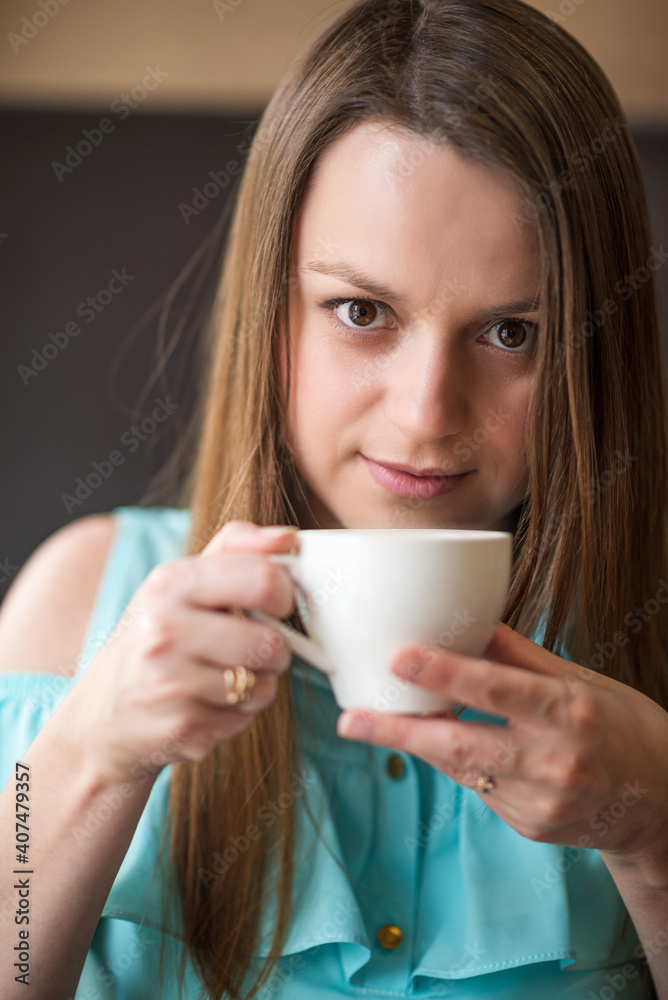 Young beautiful girl with brown hair drinks coffee in a cafe. Young beautiful girl with brown hair drinks coffee in a cafe.