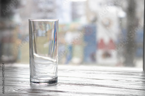 An empty clear glass tumbler on the table by the window.