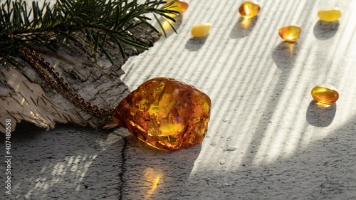 Fényképezés Sparkling yellow orange Baltic amber pendant with water drops on a birch bark