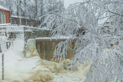 Waterfall in winter, strong current, frozen ice
  and trees in other. landscape photography
  Frost, ice, cold concept. Old town in Helsinki photo