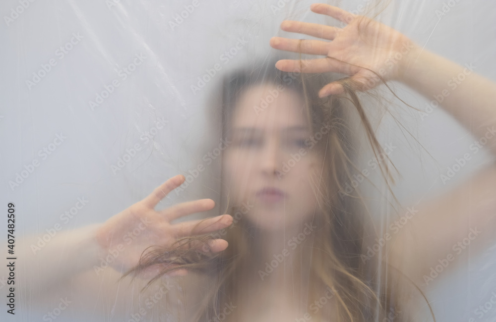 Fototapeta premium fantastic outstanding strange portrait with protective defensive hands in anxiety dream of beautiful sexy sensual woman behind transparent plastic foil as background, copy space