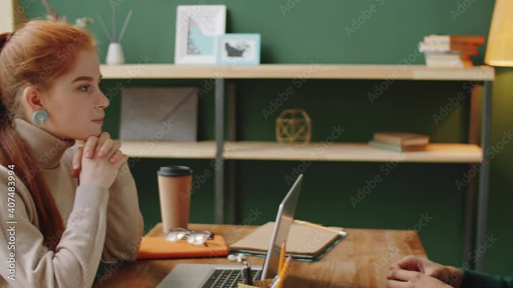 PAN shot of young cheerful business lady smiling and discussing job with young handsome mixed race man while cooperating in office PAN shot of young cheerful business lady smiling and discussing job with young handsome mixed race man while cooperating in office