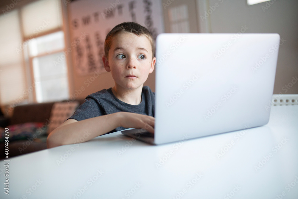 boy looking at a laptop with a worried and confused look boy looking at a laptop with a worried and confused look