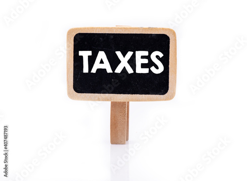 TAXES word on small chalkboard and white background. Concept for business.