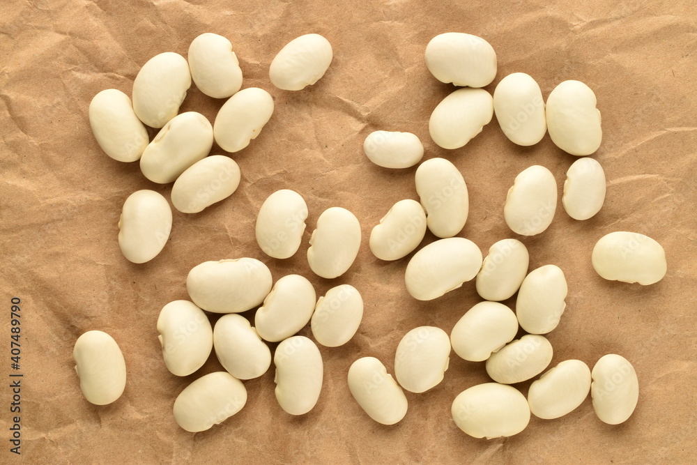 Several dried grains of organic white beans on brown paper, top view. Several dried grains of organic white beans on brown paper, top view.