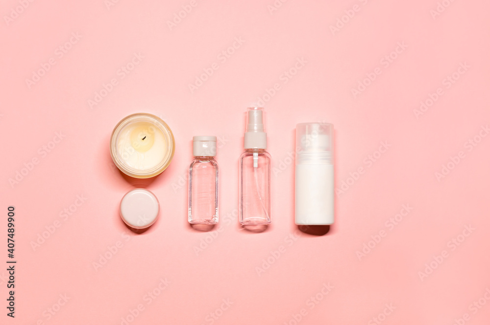 Minimalistic layout with a simple composition: face lotion, toner, cream, lip balm, and a lighted candle on a pink background.
