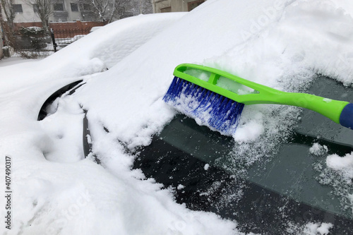 Сar snow brush cleans thick layer of snow and ice on frozen car glass. Windshield is covered with snow, Weather winter condition. photo