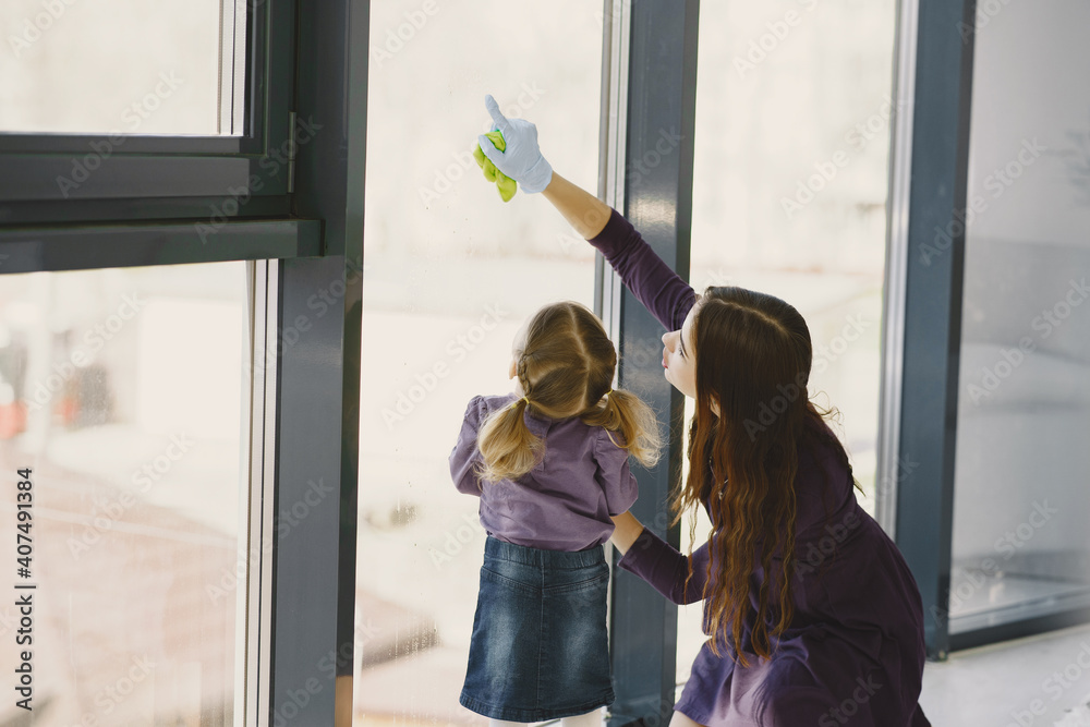 Woman and her little daughter cleaning window. Family at home. Woman and her little daughter cleaning window. Family at home.