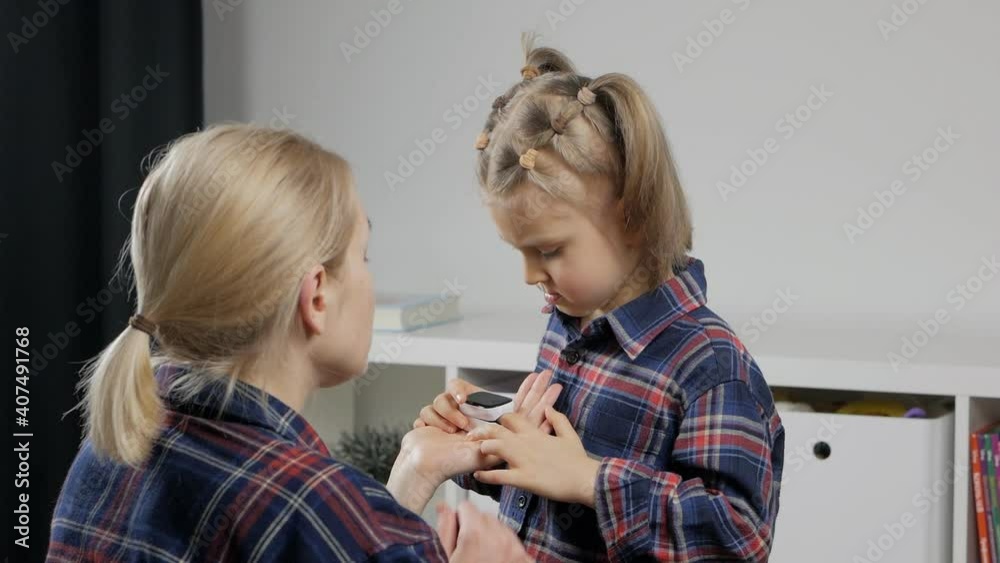 A mother measures her daughter's oxygen saturation with a digital pulse oximeter at home. A mother measures her daughter's oxygen saturation with a digital pulse oximeter at home.