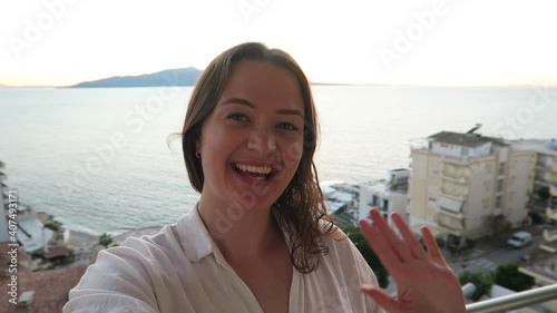 Cheerful female traveler taking a selfie on the beach from her hotel in Saranda Albania. Meditteranean, Europe.