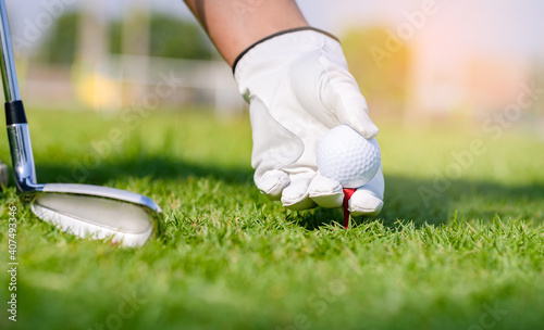 Hand in glove placing golf ball on tee in course. Golf helps to relieve tension and stimulate the brain function.