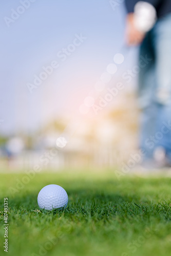 Green grass with golf ball close-up in soft focus at sunlight and have blur background with man playing golf end game successful.