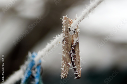 Wooden clothespin with frost on the rope