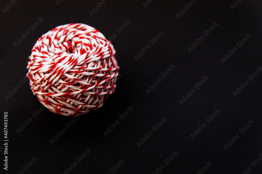 On a black background, a ball of twine is red and white. Threads for wrapping gifts. On a black background, a ball of twine is red and white. Threads for wrapping gifts.