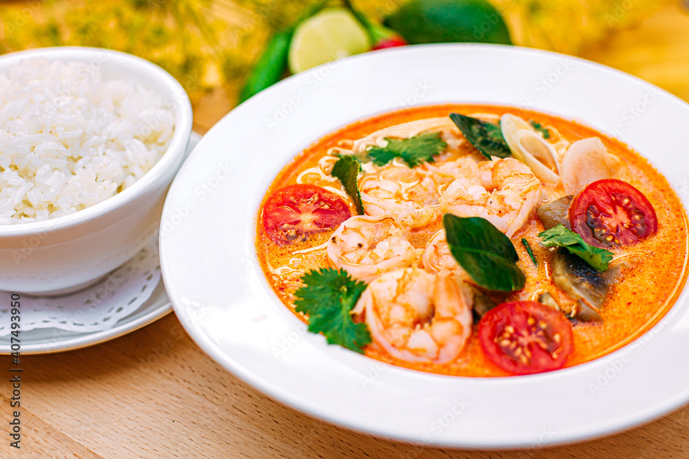 Thai soup tom yam with shrimps and tomatoes and rice as a garnish on a decorated table Thai soup tom yam with shrimps and tomatoes and rice as a garnish on a decorated table