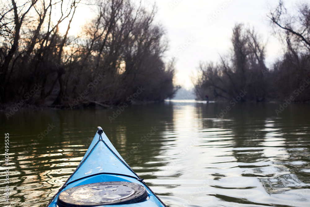 Fototapeta premium Bow (prow) of blue kayak in winter or early spring river. Winter kayaking