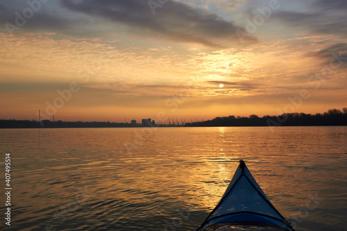 Kayakers enjoying the beautiful sunrise . Kayaking in the river during a vibrant winter sunrise with City Skyline in Background