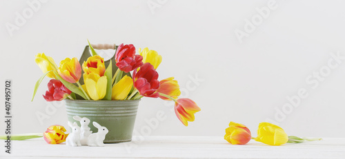 Fototapeta Naklejka Na Ścianę i Meble -  red and yellow tulips in bucket and ceramic rabbit on white background