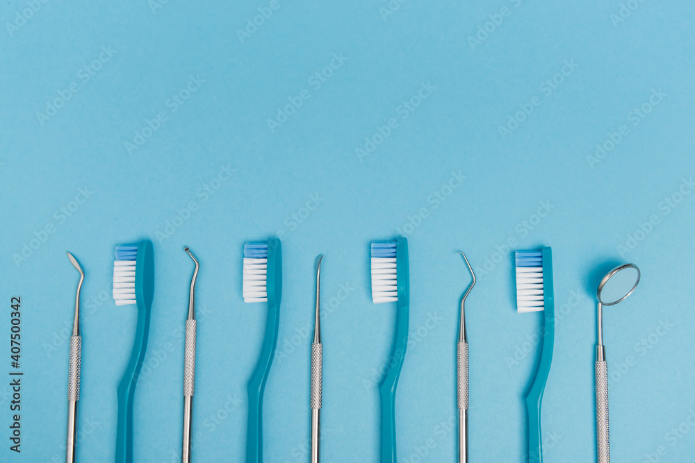 Top view of toothbrushes and dental tools on blue background with copy space Top view of toothbrushes and dental tools on blue background with copy space