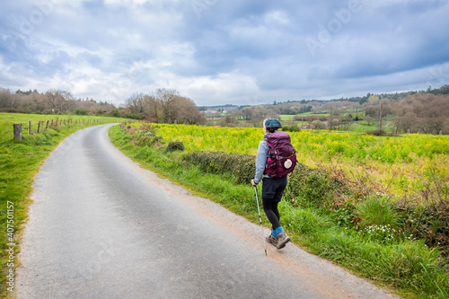 Fototapeta Naklejka Na Ścianę i Meble -  Pilgrim Girl with Hiking Gear Walking in Forest and Fields in Galicia Spain along the Way of St James - Camino de Santiago Pilgrimage Trail