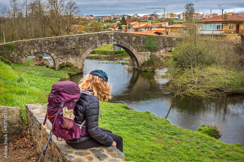 Pilgrim Girl Looking at Medieval Stone Bridge Puente San Xoan in Furelos along the Way of St James Camino de Santiago photo