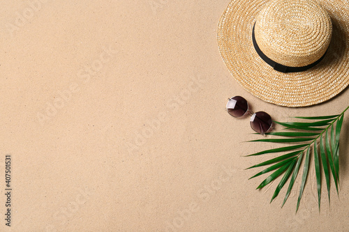 Fototapeta Naklejka Na Ścianę i Meble -  Straw hat, sunglasses, palm leaf and space for text on beach sand, flat lay. Summer vacation