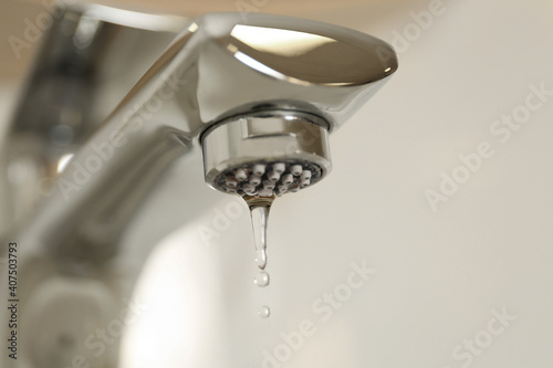 Φωτογραφία Water drops falling down from tap on light background, closeup