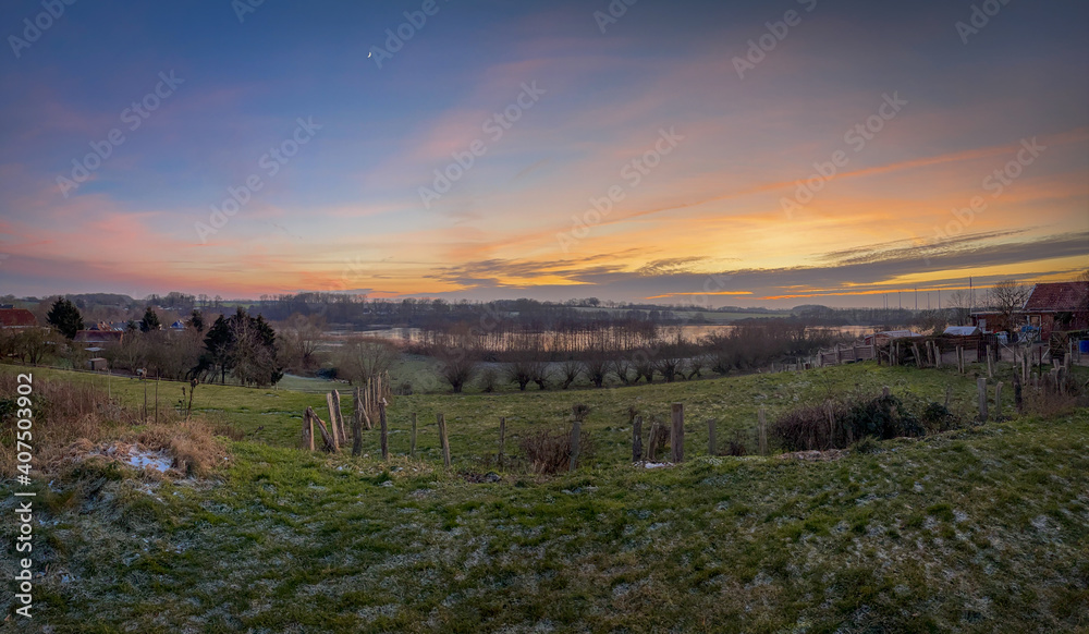 Fototapeta premium a panoramic shot of a landscape with lake in the sunset