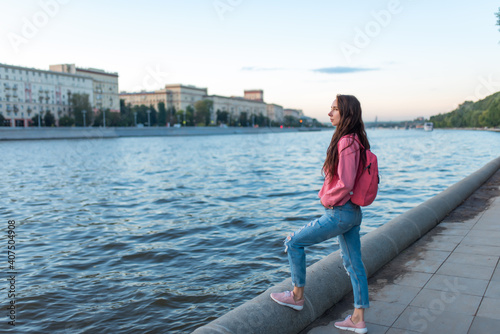 woman in summer in city stands by river bank, free space for a copy of the text, a date and meeting on the street, travel and enjoying a weekend. Lake pond and water in city.