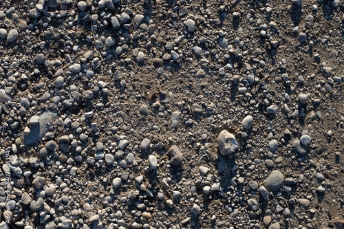 Grey pebbles and soil texture. Small river pebbles background