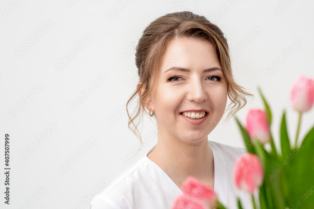 Portrait of a happy young caucasian woman with pink tulips against a white background Portrait of a happy young caucasian woman with pink tulips against a white background