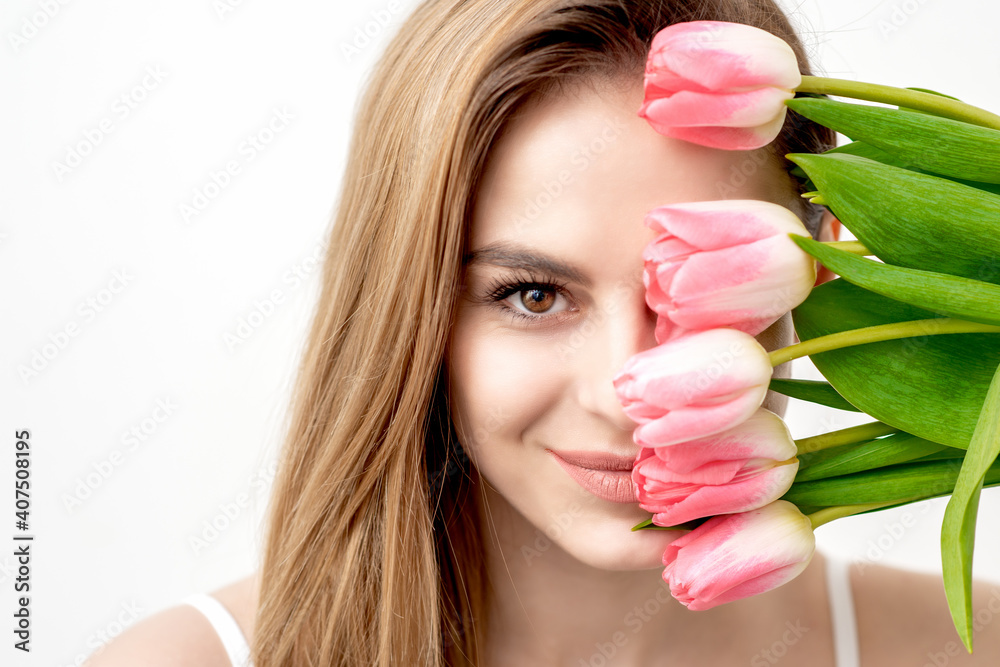 Portrait of a happy young caucasian woman with pink tulips against a white background