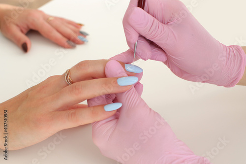 The master in pink gloves makes the girl manicure on nails blue. High quality photo