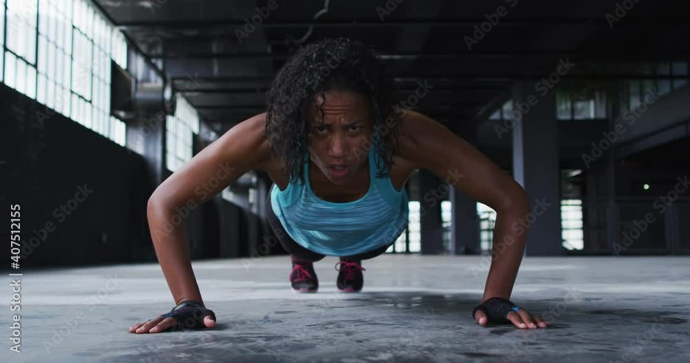 African american woman doing push ups in an empty urban building