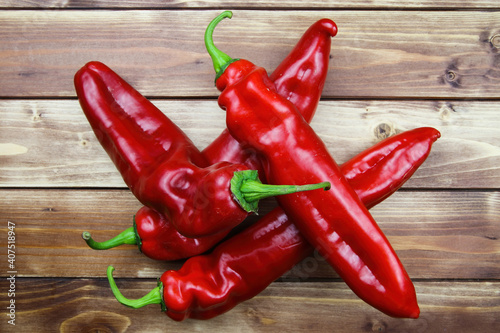 Closeup of isolated group 4 red ripe raw pointed peppers pile, wood timber planks background