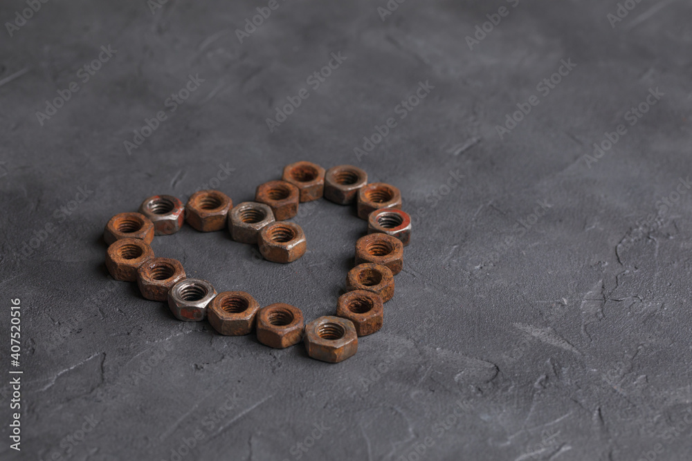 Heart made of small rusty nuts. Machine parts. Items on a dark background. Heart made of small rusty nuts. Machine parts. Items on a dark background.