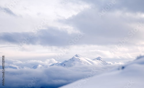 Spektakulärer Blick auf verschneite Berge im Winter in einem Meer von Wolken