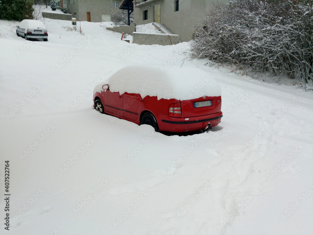 Red car surrounded by snow and with the top of the vehicle completely covered with snow, in winter, in Vetraz-Monthoux in Haute-Savoie Red car surrounded by snow and with the top of the vehicle completely covered with snow, in winter, in Vetraz-Monthoux in Haute-Savoie