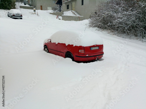 Red car surrounded by snow and with the top of the vehicle completely covered with snow, in winter, in Vetraz-Monthoux in Haute-Savoie