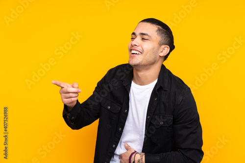 Asian handsome man isolated on yellow background showing thumb down with two hands