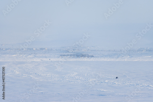The car drives along the winter ice crossing over the Anadyr estuary. Travel to the extreme North of Russia in the Arctic. Cold frosty winter weather. Anadyr, Chukotka, Siberia, Russian Far East.