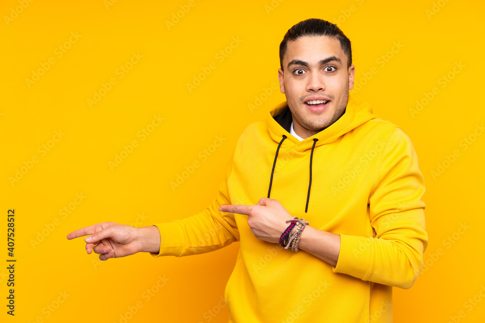 Asian handsome man isolated on yellow background shouting with mouth wide open to the side Asian handsome man isolated on yellow background shouting with mouth wide open to the side