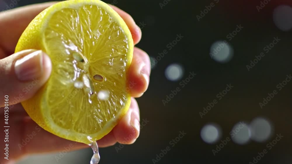 Close-up, a woman hand is squeezing a lemon in slow motion. Lemon squeezed in slow motion.