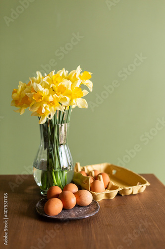 Beautiful festive Easter still life. A bouquet of daffodils in a glass vase and painted eggs are on the table. Spring mood. Colorful minimalistic postcard. Flowers yellow narcissus springtine photo