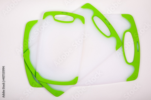 Set of white kitchen cutting boards with green handles for cooking.