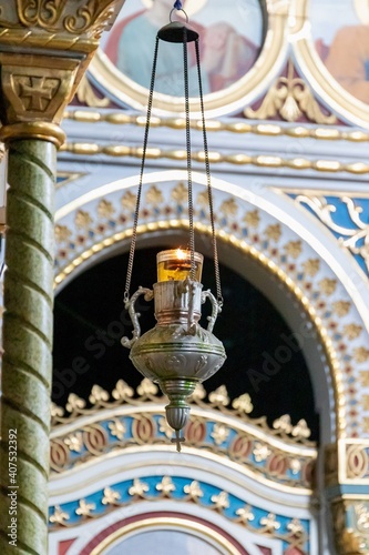 Hanging church lamp with a lit candle on a chain © ok_fotoday