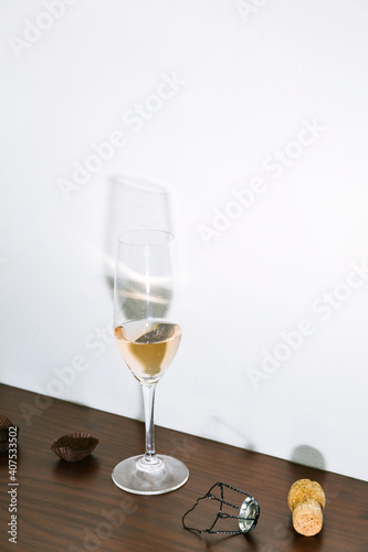 Single glass of pink rose wine in champagne flute with candy wrappers, cork, and muselet on table