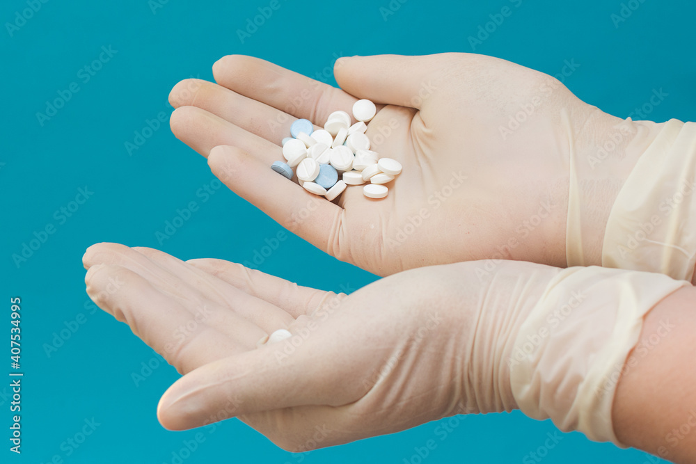 hands in gloves on a blue background hold a lot of pills. Pills in the palms. The concept is treatment, a lot of medications. horizontal photo, close-up. hands in gloves on a blue background hold a lot of pills. Pills in the palms. The concept is treatment, a lot of medications. horizontal photo, close-up.