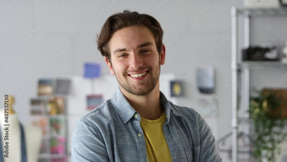 Portrait of smiling male clothes designer by desk in fashion studio - shot in slow motion Portrait of smiling male clothes designer by desk in fashion studio - shot in slow motion
