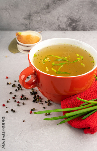 hot homemade vegeterian vegetable broth with amino acids in red bowl
